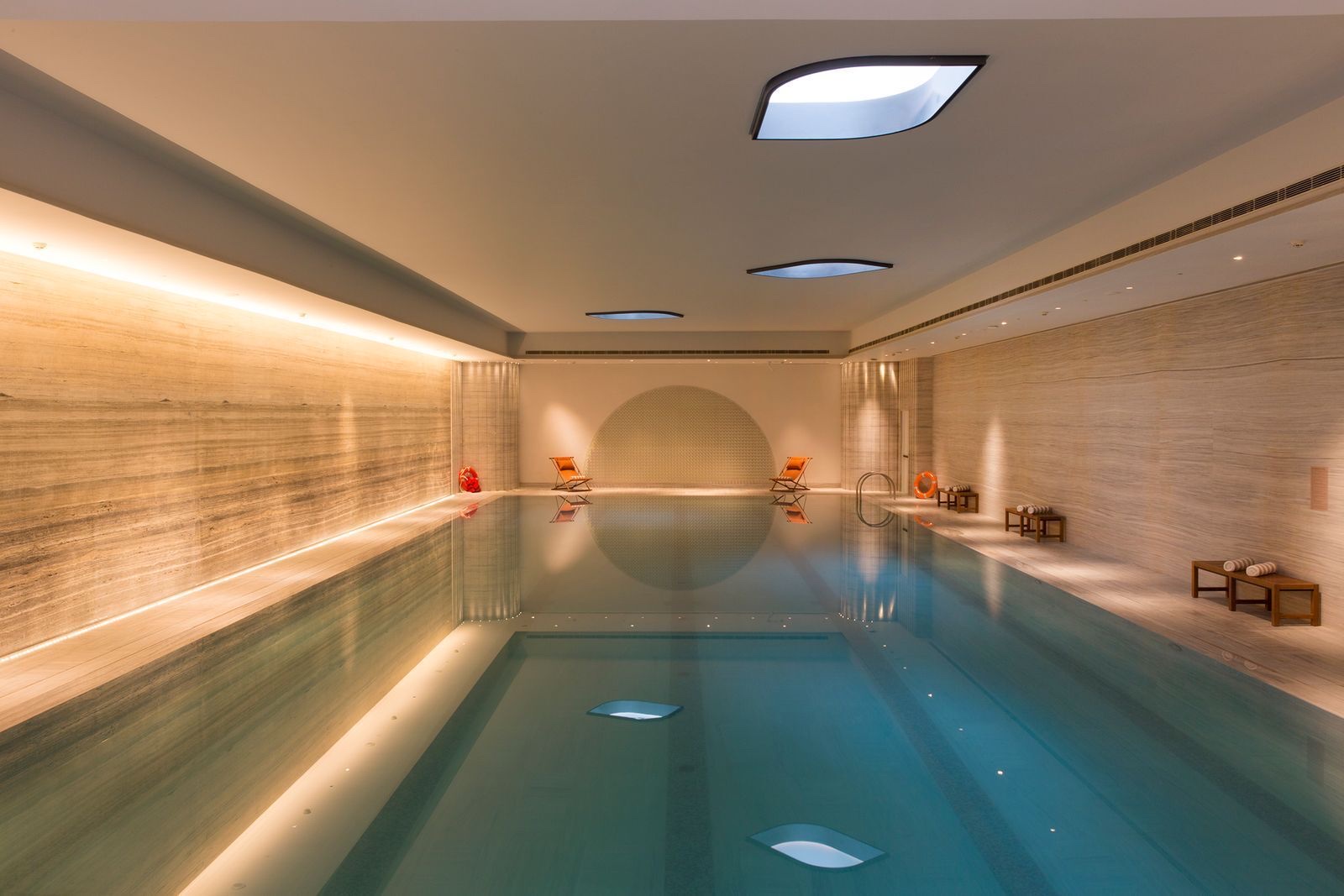 Indoor lap pool with stone walls and skylights