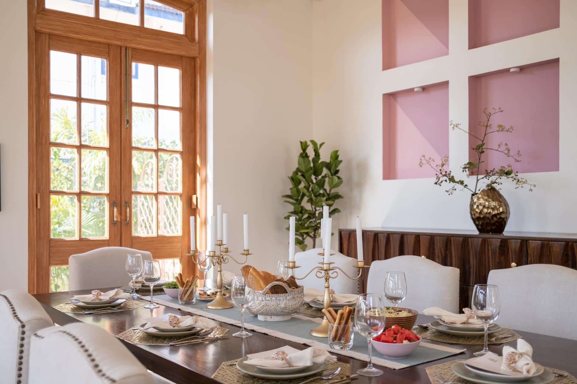 Dining table set beneath tall timber-framed windows (Isprava Villa Sobreda)